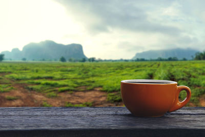 Coffee cup on table against sky