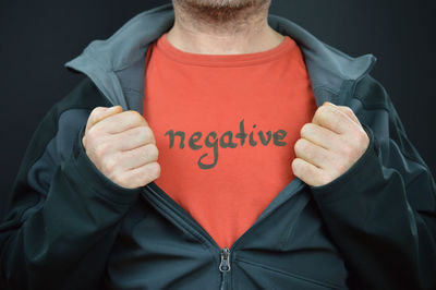 Midsection of man holding text against black background