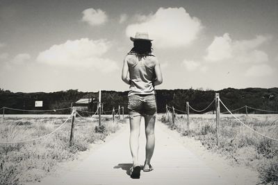 Rear view of woman walking on footpath against sky