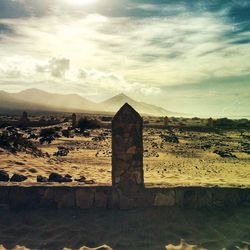 Built structure on landscape against cloudy sky