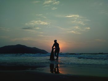 Silhouette of man at beach against sky during sunset