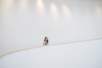 Low angle view of woman standing against white wall
