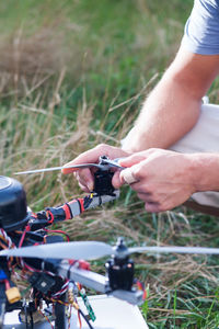 Cropped hands of man with drone on grassy field