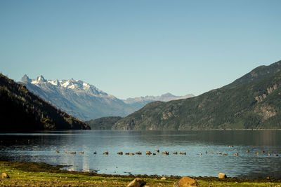 Scenic view of lake by mountains against clear sky