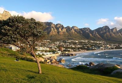 Scenic view of sea and mountains in front of grassy hill against sky