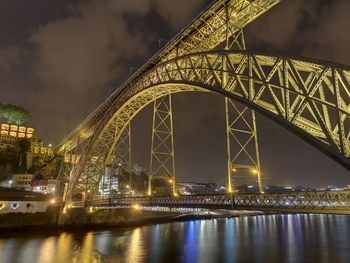 Illuminated bridge over river against sky at night