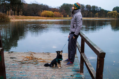 Rear view of woman with dog standing by lake