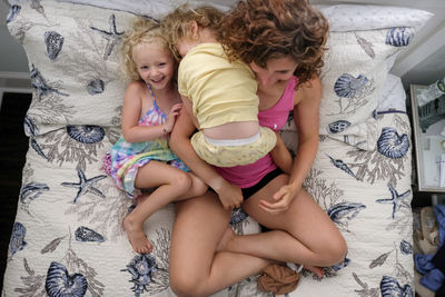 High angle view of mother with daughters sitting on bed at home