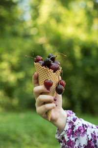 Close-up of woman holding cherries in waffle cone