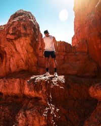 Man standing on rock against sky