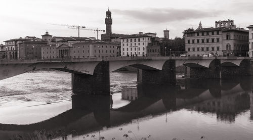 Arch bridge over river against buildings in city