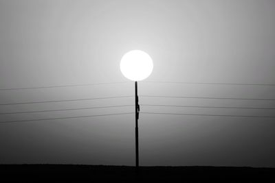 Silhouette electricity pylon against sky during sunset