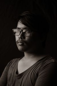 Portrait of young man wearing hat against black background