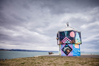 Colorful lifeguard hut at beach against cloudy sky