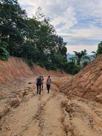 Rear view of people walking on road against sky