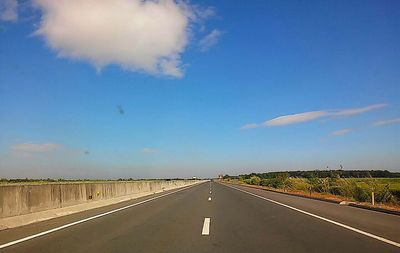 Road by street against blue sky