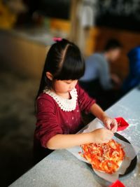 High angle view of girl preparing food at table in kitchen