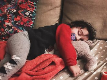 Baby boy sleeping with toy on bed at home