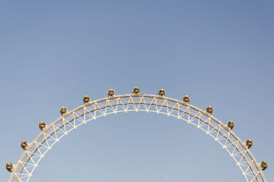 Low angle view of ferris wheel against clear blue sky