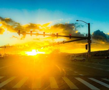 Cars on road against sky during sunset