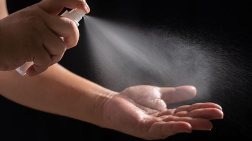 Close-up of hand holding cigarette over black background