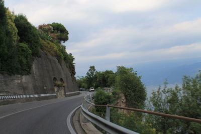 Road by trees against sky