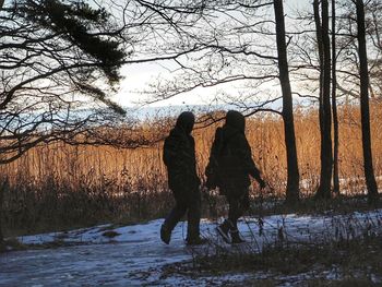 Rear view of people walking on snow covered landscape