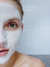Close-up portrait of woman with facial mask in bathroom