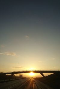 Silhouette bridge over river against sky during sunset