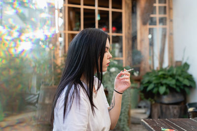 Young woman smoking while sitting by table