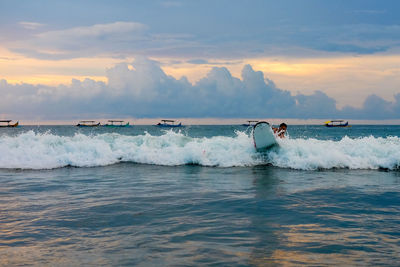 Man surfboarding in sea against sky