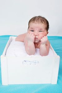 Portrait of cute baby girl lying on box with soft blanket