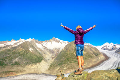 Full length of man standing on mountain against blue sky