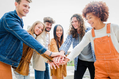 Cheerful friends stacking hands outdoors