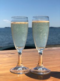 Close-up of drinks on table against sea