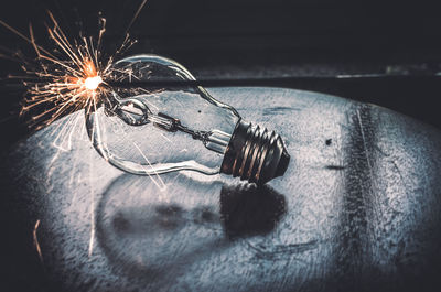 Close-up of light bulb with sparks on table