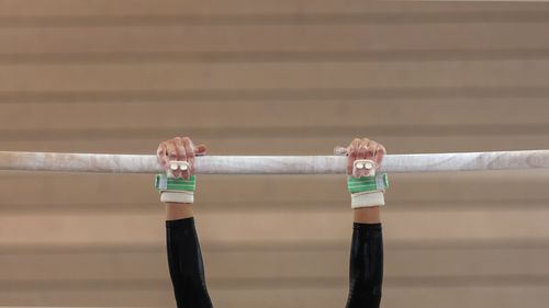 Cropped hands of person hanging on bamboo