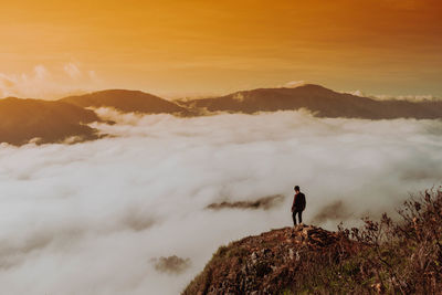 Man standing on mountain against sky during sunset