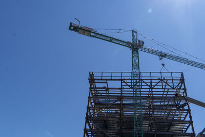 Low angle view of crane against clear blue sky