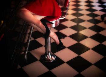 Low section of woman holding umbrella on tiled floor