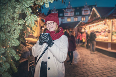 Portrait of smiling woman having coffee at city during winter