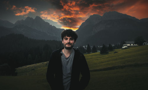 Portrait of young man standing on mountain against sky