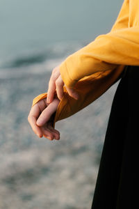 Midsection of man holding sea against sky