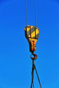 Low angle view of crane against clear blue sky