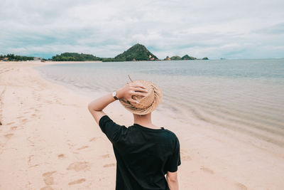 Rear view of men standing on shore at beach