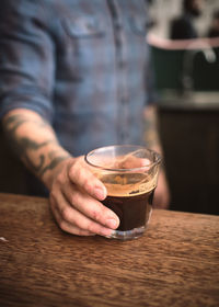 Midsection of man holding coffee cup on table