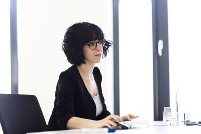 Young woman using mobile phone while sitting on table