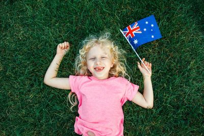Cute girl holding australian flag lying down at lawn
