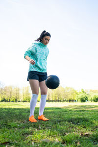 Full length of woman playing soccer on field