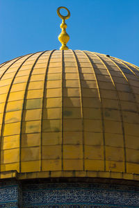 Low angle view of yellow building against clear blue sky